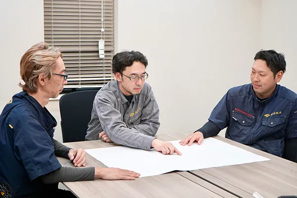 男性社員3人が話し合っている画像です