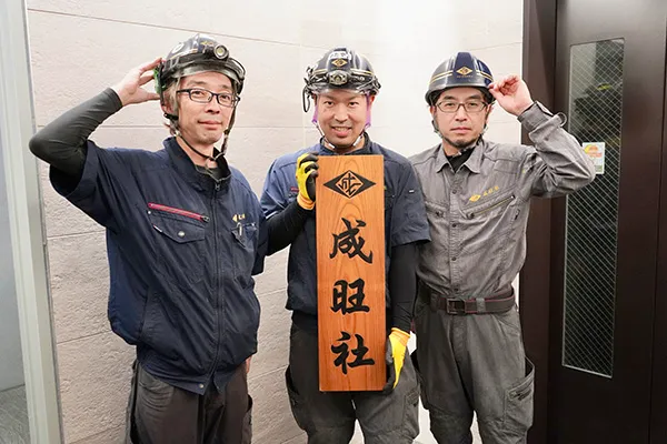 男性社員3人が看板を持っている画像です